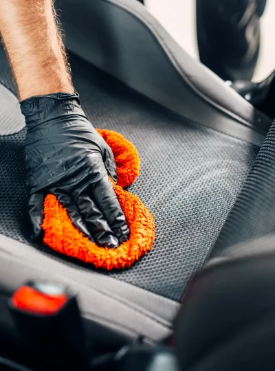 Professional chemical cleaning of car seats with spoonge. Carwash service, male worker in gloves using special agent